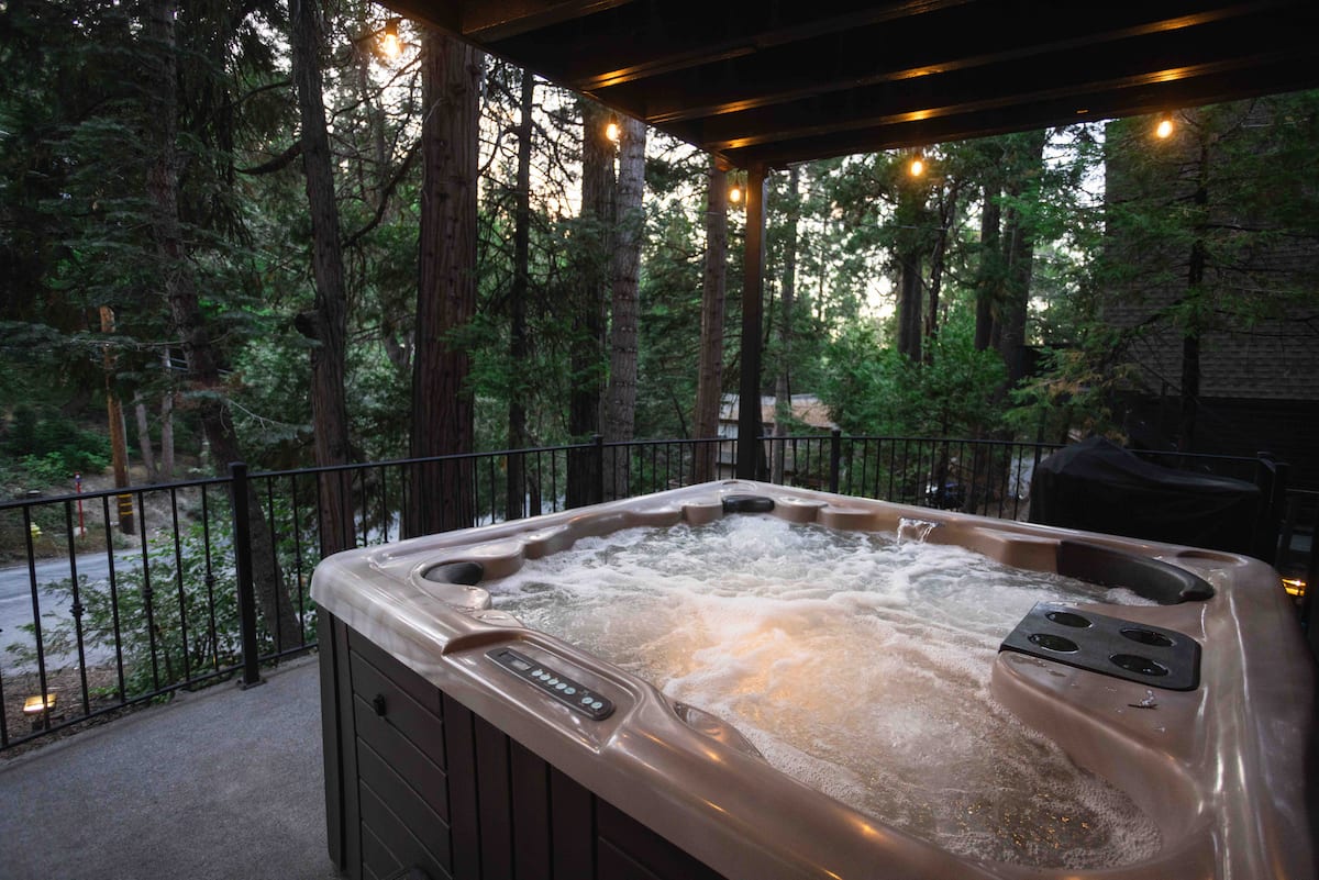 Private hot tub at Cloud Break Cabin surrounded by pine trees at sunset